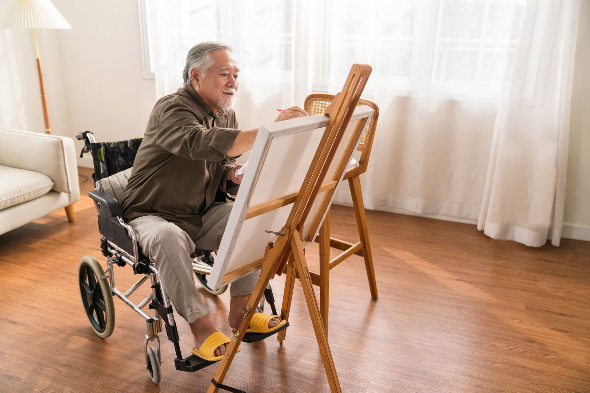 old-senior-asian-male-using-art-therapy-while-his-legs-is-injured-homeasian-elder-man-spend-recovering-his-leg-is-getting-better-with-painting-canvas-art-living-room-home